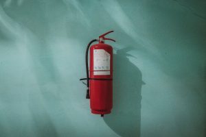 Red fire extinguisher against a green wall
